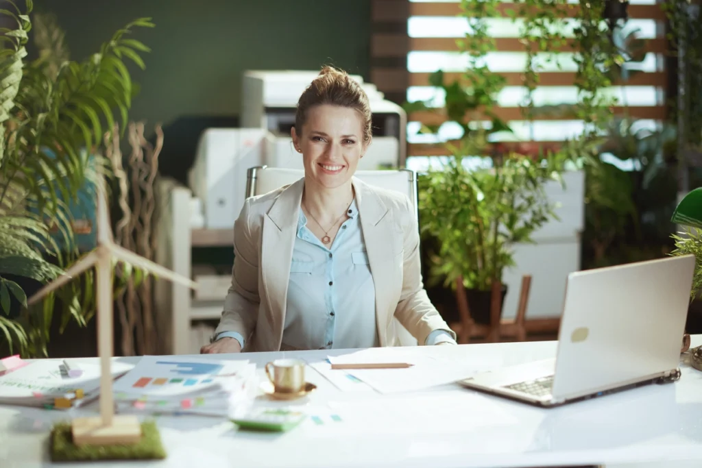 smiling environmental consultant with a laptop on the desk and a wooden windmill
