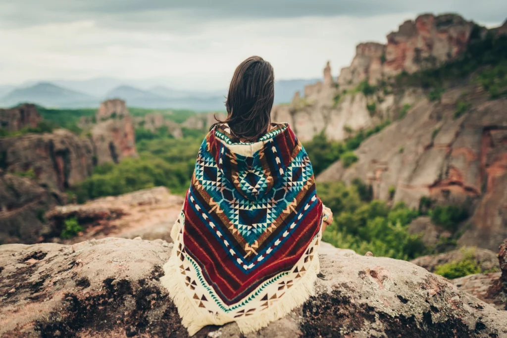 woman wearing American Indian tribal clothes while looking at a historical mountain site