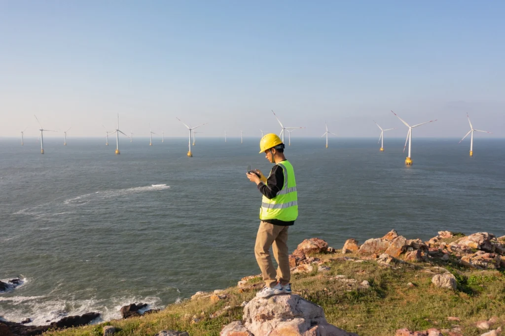 man performing a Phase I ESA with windmills as background