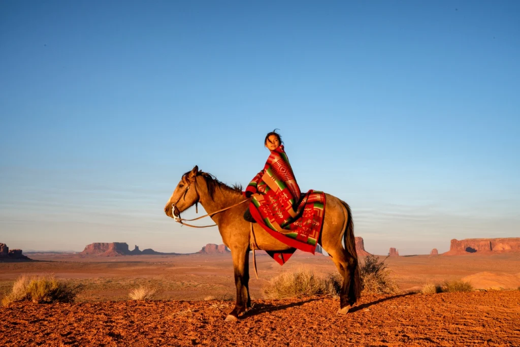 canyon with woman wearing traditional american indian clothes on a horse