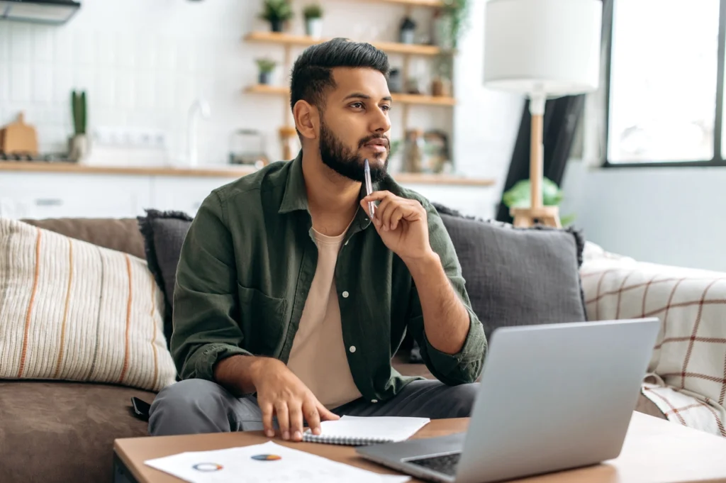 man thinking about the Phase I ESA process with laptop and notebook in table