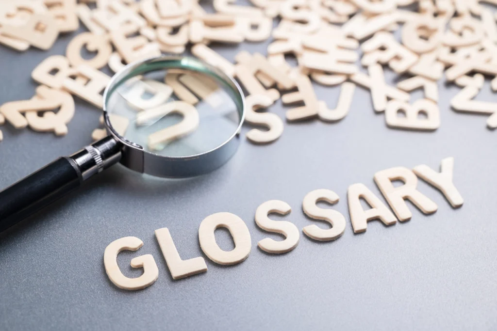 magnifying glass on scattered letters and a formed word at the bottom saying glossary